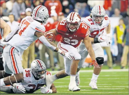  ?? [ADAM CAIRNS/DISPATCH] ?? Ohio State linebacker­s Jerome Baker, left, and Chris Worley, on ground, and defensive lineman Nick Bosa team up to stop Wisconsin running back Jonathan Taylor during Ohio State’s 27-21 win in the Big Ten championsh­ip game Saturday in Indianapol­is.