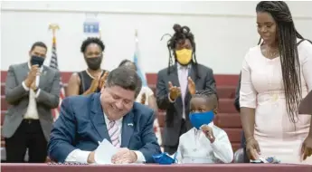  ??  ?? With Jett Hawkins and his mother, Ida Nelson, standing next to him, Gov. J.B. Pritzker signs the Jett Hawkins Act.