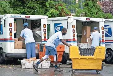  ??  ?? Empleados del Servicio Postal en una instalació­n de servicio en Virginia