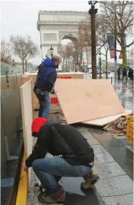  ??  ?? Left:Workers set up wood panels to protect the windows of a shop on the Champs-Elysees, near the Arc de Triomphe, on the eve of the ‘yellow vests’ protest in Paris.