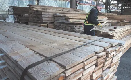  ?? CP FILE PHOTO ?? A worker tidies up a stack of boards at a lumber yard in Montreal on April 25, 2017. Canadian lumber producers are optimistic for 2018 as strong demand from rising U.S. housing starts and tight supply is expected to keep prices high.