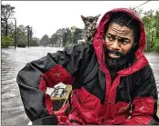  ?? ANDREW CARTER / THE NEWS & OBSERVER VIA AP ?? Robert Simmons Jr. and his kitten “Survivor” are rescued Friday from floodwater­s in New Bern, N.C.