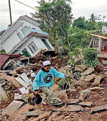  ?? AP ?? A youth navigates his way through the rubble at a village affected by Monday’s earthquake in Cianjur, West Java. More rescuers and volunteers were deployed yesterday.