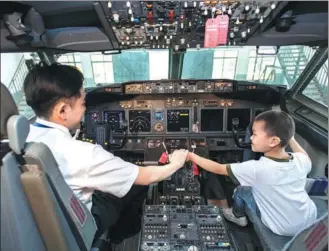  ?? XIONG QI / XINHUA ?? A boy with a hearing disability in Hubei province — one of a group of hearing-impaired children invited by China Southern Airlines — gets a taste of what it’s like to be a pilot while visiting the company’s facility in Wuhan, Hubei province, on Tuesday.