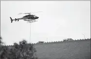  ?? Appeal-Democrat file photo ?? A helicopter carries a load of material to repair the emergency spillway at Oroville Dam in February.