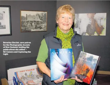  ?? ?? Beverley Sinclair, new patron for the Photograph­ic Society of New Zealand, holding the publicatio­ns she edited — NZ Camera and Capturing the Light.