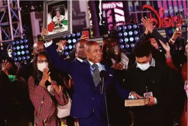  ?? Arturo Holmes / Getty Images ?? Eric Adams holds a picture of his late mother, Dorothy, as he is sworn in as the 110th mayor of New York City in Times Square shortly after the ball dropped at midnight, marking the arrival of the new year.