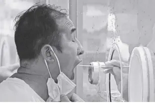  ?? AP/ANDY WONG ?? A MAN pulls his mask to get his routine Covid-19 throat swab at a coronaviru­s testing site in Beijing on Tuesday, August 9, 2022. Chinese authoritie­s have closed Tibet’s famed Potala Palace after a minor outbreak of Covid-19 was reported in the Himalayan region.