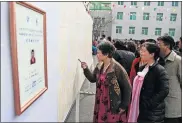  ?? [DITA ALANGKARA/THE ASSOCIATED PRESS] ?? People inspect the list of voters as a portrait of a candidate for the national legislatur­e is displayed on the left, during the election at a polling station Sunday in Pyongyang, North Korea.