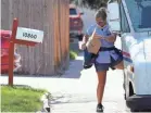  ?? TREVOR HUGHES/USA TODAY NETWORK ?? U.S. Postal Service carrier Amy Bezerra loads mail, including an Amazon package, into her delivery pouches along her route in suburban Denver.