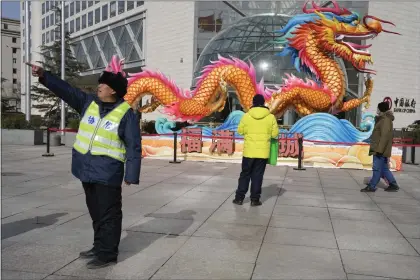  ?? NG HAN GUAN — THE ASSOCIATED PRESS ?? A municipal worker gives direction near a sculpture of a dragon in Beijing, Saturday, March 2, 2024. One burning issue dominates as the 2024sessio­n of China’s legislatur­e gets underway this week: the economy. The National People’s Congress annual meeting, which opens Tuesday, is being closely watched for any signals on what the ruling Communist Party might do to re-energize an economy that is sagging under the weight of expanded government controls and the bursting of a real-estate bubble.