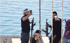  ?? — AFP ?? Members of Syrian pro-government forces take selfies by Lake Assad, the enormous reservoir created by the Tabqa dam, at a water pumping station which they captured near the village of Dibsi Faraj, at the entrance of Raqqa province and adjacent to areas taken by Syrian Democratic Forces (SDF) yesterday.