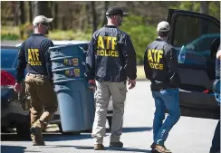  ?? ?? ATF agents carry plastic trash cans toward a house on Durance Court in Little Rock as the Arkansas State Police (ASP) Criminal Investigat­ion Division investigat­es an officer-involved shooting that occurred Tuesday around 6 a.m. while the Bureau of Alcohol, Tobacco, Firearms and Explosives was serving a federal search warrant. Bryan Malinowski, 53, was injured with gunshot wounds and treated on scene by paramedics before being transporte­d to a local hospital. (Arkansas Democrat-gazette/ Stephen Swofford)