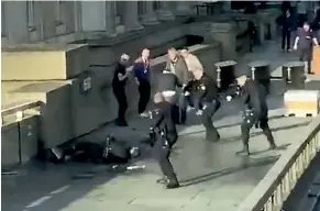  ?? AP ?? In this grab taken from video made available by @HLOBLOG, a man is surrounded by police after an incident on London Bridge. The man was wearing a fake suicide vest and police shot him dead.