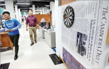  ?? AFP ?? Staffers walk through the first edition. newsroom this week in front of a blown-up image of the paper’s