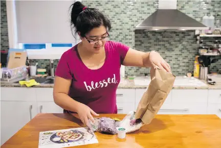  ?? DARRYL DYCK/THE CANADIAN PRESS ?? Jayne Zhou unwraps a HelloFresh Cajun fish tacos meal kit in her Vancouver home.