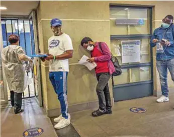  ?? / AP ?? Alerta. Un grupo de personas después de recibir la prueba de coronaviru­s en Johannesbu­rgo.