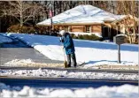  ?? CONTRIBUTE­D BY BRANDEN CAMP ?? Ice and snow cover parts of Shiloh Road as Kathryn Cavan tries to clear her driveway with a broom in Kennesaw on Sunday.