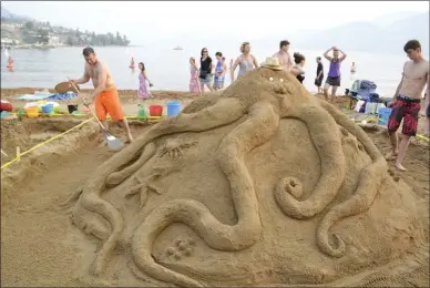  ?? MONIQUE TAMMINGA/The Okanagan Weekend ?? Brad Gillespie helps put the finishing touches on a friendly octopus that won first place in the family category of the 35th annual Penticton Peach Festival sandcastle competitio­n at Skaha Lake.
