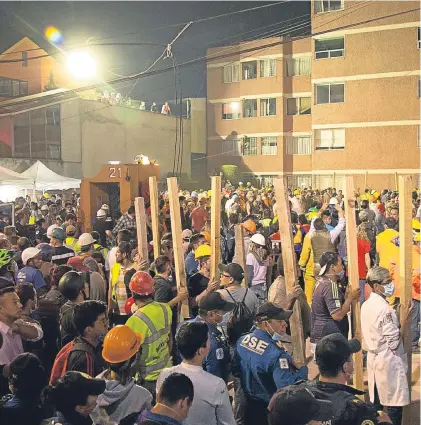  ?? Picture: AP. ?? Volunteers bring pieces of wood to help prop up sections of the collapsed school.