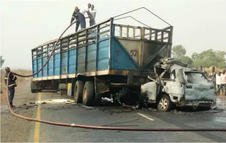  ?? Photo: abubakar Sadiq Isah ?? Scene of an accident in which two persons were burnt to death after a car rammed into a trailer. Fire service men try to put out the fire at the scene on Abuja-Lokoja road yesterday.