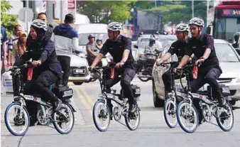  ??  ?? ... Members of the Tourist Police Unit try out e-bicycles for crime prevention rounds yesterday. Seven e-bicycles were handed over by three private firms to state police chief Commission­er Datuk Chuah Ghee Lye as part of their corporate social...