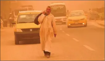  ?? ?? A man walks on a street during a sandstorm.