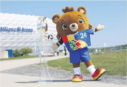  ?? Picture: AFP ?? GETTING CLOSER. Albaert, mascot for Euro 2024, poses next to the tournament’s trophy and ball in front of the Allianz Arena in Munich this week ahead of next month’s showpiece.