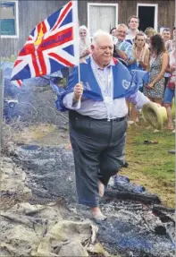  ??  ?? Council leader Gerry Clarkson does the firewalk to raise money for Charing Scouts - and has to cool his feet in a bucket of water after suffering a burn