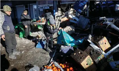  ?? ?? People clear up after the attack on the Tekstilshc­hik suburb of the city. Photograph: AlexanderE­rmochenko/Reuters