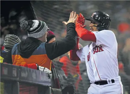  ?? CHRISTOPHE­R EVANS / BOSTON HERALD ?? CROWD PLEASER: Mookie Betts gets a high five from a fan after scoring a run during the Red Sox’ Game 2 victory at Fenway. Betts quickly has grown into a leadershio role and become a solid MVP favorite this season.