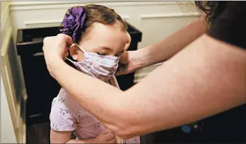  ?? BRYNN ANDERSON/AP ?? Rachel Adamus helps her daughter, Neva, 5, put on her mask before her first day of kindergart­en Monday in Dallas, Georgia. President Donald Trump has urged schools to reopen.