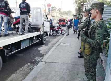  ?? CONTRIBUTE­D FOTO ?? CHECKPOINT. Soldiers stand guard as members of the Inter-Agency Council for Traffic check the motorists’ documents in Barangay Linao, Talisay City .