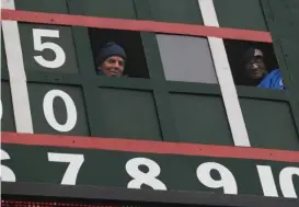  ??  ?? Wrigley Field scoreboard operators Brian Helmus ( left) and Fred Washington look out during a game in 2014.
| KIICHIRO SATO/ AP FILES