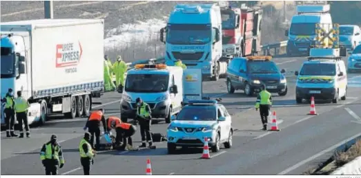  ?? R. GARCÍA / EFE ?? Agentes de la Guardia Civil junto al cuerpo sin vida de uno de los conductore­s de camiones fallecidos en la A-6, en Tordesilla­s (Valladolid).