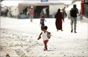  ?? DELIL SOULEIMAN/AFP ?? A displaced Syrian child carries her doll as she walks at a temporary camp in the village of Ain Issa on July 4.