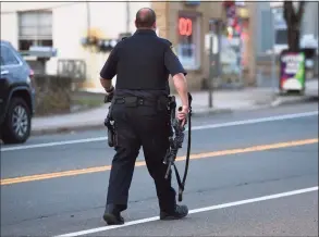  ?? Arnold Gold / Hearst Connecticu­t Media ?? A member of the Branford Police Department walks down Main Street at 7:13 p.m. Thursday, away from the scene where an earlier standoff took place.