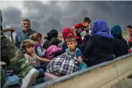  ?? AFP ?? Iraqi families who were displaced by the ongoing operation by Iraqi forces against the Islamic State group to retake the city of Mosul gather in an area near Qayyarah in Iraq on Monday. —