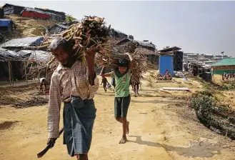  ?? Wong Maye-E / Associated Press ?? Rohingya Muslim men and boys carry firewood back to their tents at Gundum refugee camp on Thursday in Bangladesh. Since late August, more than 620,000 Rohingya have fled Myanmar’s Rakhine state into neighborin­g Bangladesh, seeking safety from “ethnic...