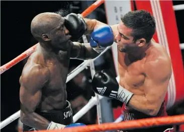  ?? BERTRAND LANGLOIS/ AFP/GETTY IMAGES ?? Antonin Décarie, right, dishes out some punishment to Souleymane M’baye during their WBA World Championsh­ip welterweig­ht match at the Marcel Cerdan hall in Levallois, near Paris, in 2010. Décarie lost to M’baye.