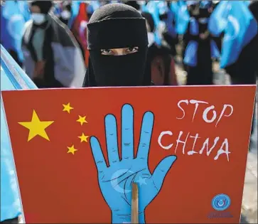  ?? Emrah Gurel Associated Press ?? A PROTESTER from the Uyghur community holds a sign during a visit to Turkey last month by China’s foreign minister. Uyghurs, protesting their treatment in China, want action ahead of the 2022 Olympics.