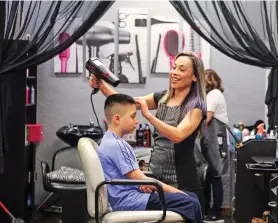  ?? GABRIELA CAMPOS/THE NEW MEXICAN ?? Liz Vigil blow-dries 11-year-old Dominic Bustos’ hair. Vigil, a Peñasco native, took ownership of the DeVargas Center salon in early February.