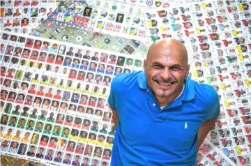  ??  ?? Gianni Bellini, owner of the largest Panini football stickers collection in the world, poses for a picture with collectabl­e stickers by Panini in his studio in San Felice sul Panaro, Modena.