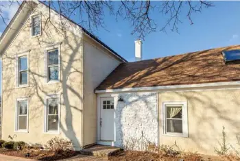  ??  ?? Below: A panel of decorative shingles draws attention to the front entry and adds architectu­ral interest to the stucco facade of the 1880s farmhouse.