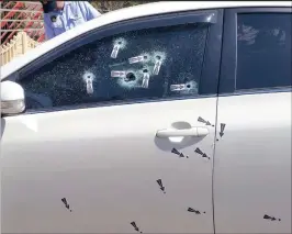  ??  ?? Sixteen bullets struck the passenger side of the Toyota Corolla seen marked by police crime scene stickers.