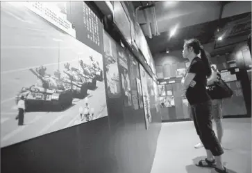  ?? Vincent Yu Associated Press ?? VISITORS to the June 4 Museum in Hong Kong take in an image of the protester who brief ly stopped a column of tanks during the crackdown on the 1989 pro-democracy demonstrat­ion in Tiananmen Square.