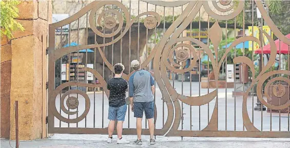  ?? AP ?? Espera. Dos chicos husmean detrás de la puerta de uno de los parques temáticos de Disney World en Orlando, que reabren este sábado.