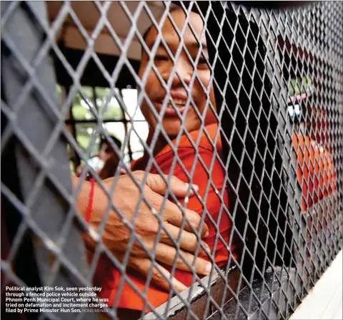  ?? HONG MENEA ?? Political analyst Kim Sok, seen yesterday through a fenced police vehicle outside Phnom Penh Municipal Court, where he was tried on defamation and incitement charges filed by Prime Minister Hun Sen.