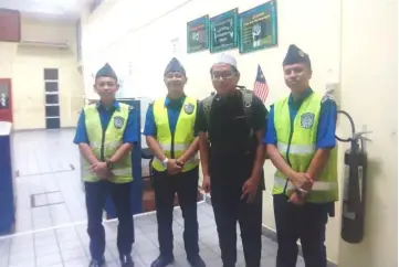  ??  ?? Muhammad Yusop pictured with security guards upon arriving at the Brunei-Limbang border.