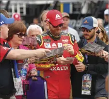  ??  ?? Dale Earnhardt Jr. signs autographs in the garage before practice for the NASCAR Cup Series auto race Saturday in Brooklyn, Mich. AP PHOTO